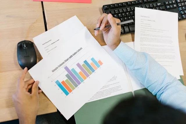 A business analyst reviews a colorful bar chart and documents at a desk, indicating data analysis. How to improve programmatic advertising for business teams: the parts worth your time